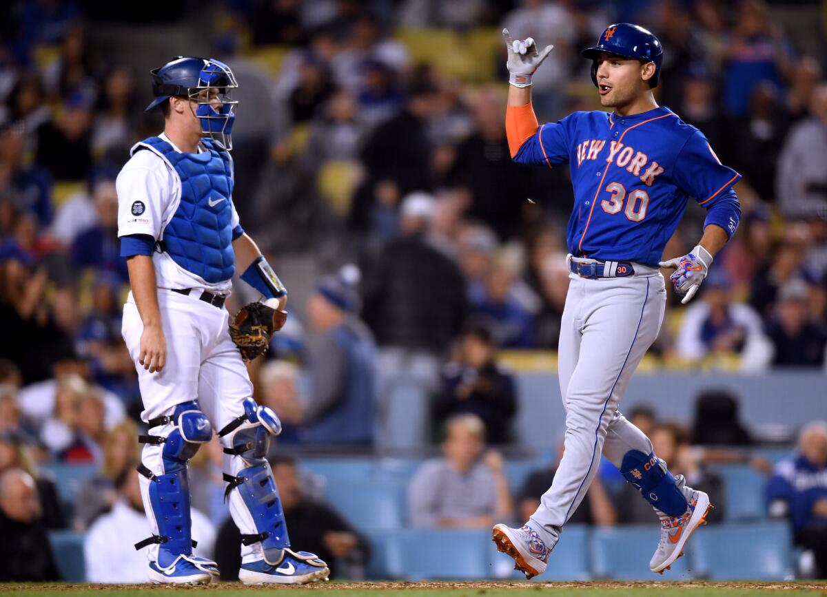 New York Mets' Michael Conforto, right, reacts to his grand slam homerun in front of Dodgers catcher Will Smith to take a 6-2 lead during the seventh inning at Dodger Stadium on Tuesday.