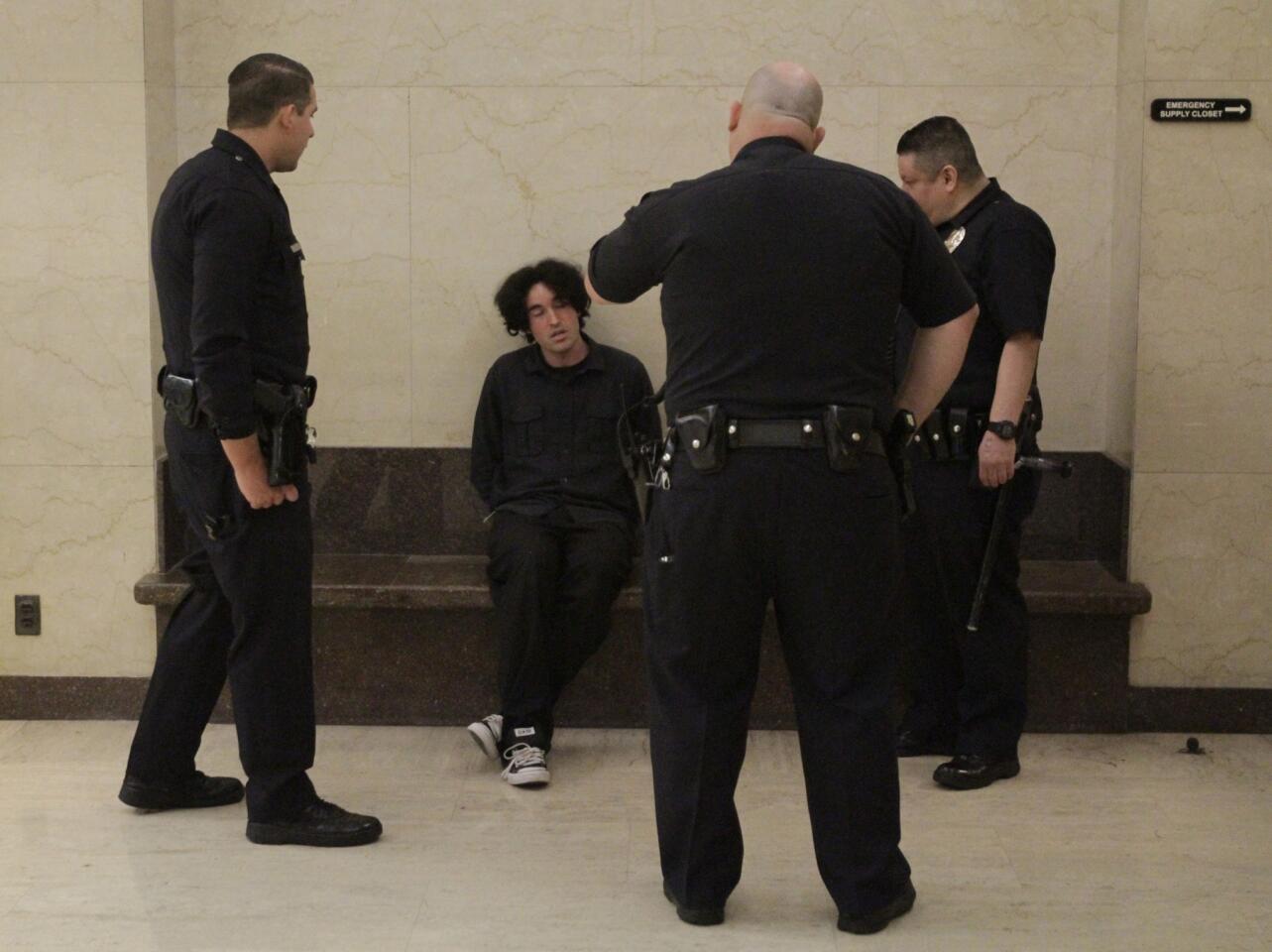 Los Angeles police talk to a man taken into custody in the lobby of the Los Angeles Times building in downtown Friday night after he allegedly made a threat. The man is an employee of VXI Global Solutions, a tenant in the building.