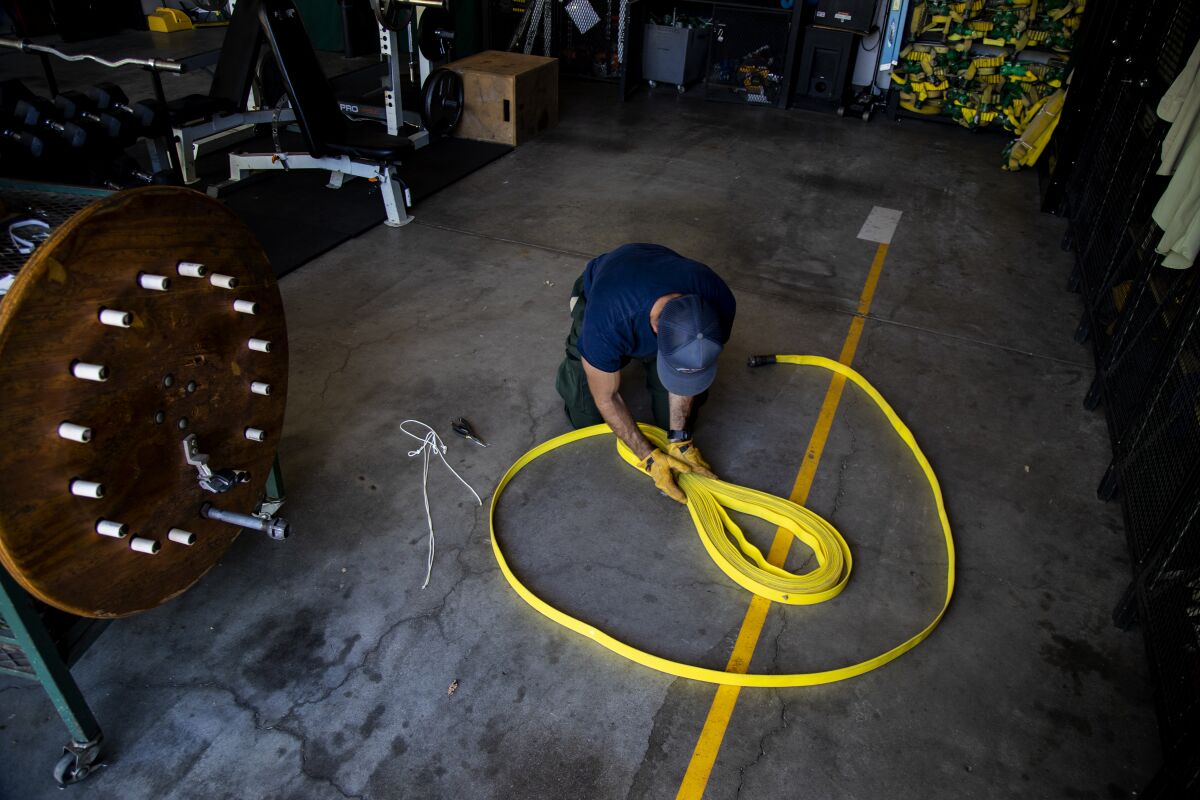 Firefighter Nick Browne folds a hose line at the Oak Flat Fire Station in Castaic.