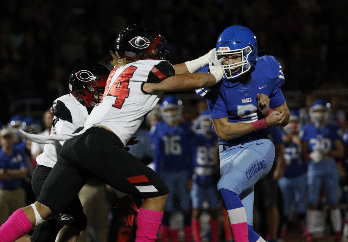 Norco quarterback Kyle Crum gets poked in the eye by Corona Centennial defender Demarieon Young after releasing a pass