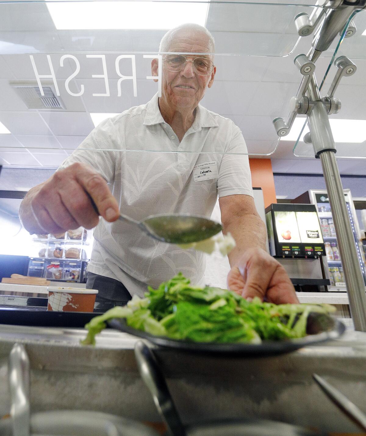Phil Downs of La Crescenta makes a salad at USC Verdugo Hills Hospital on a recent Thursday. The hospital is offering seniors a 30% discount from 4 to 8 p.m., seven days a week, to encourage seniors to socialize over healthy meals.