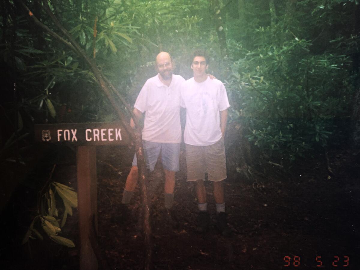 Two men pose next to a sign that says Fox Creek