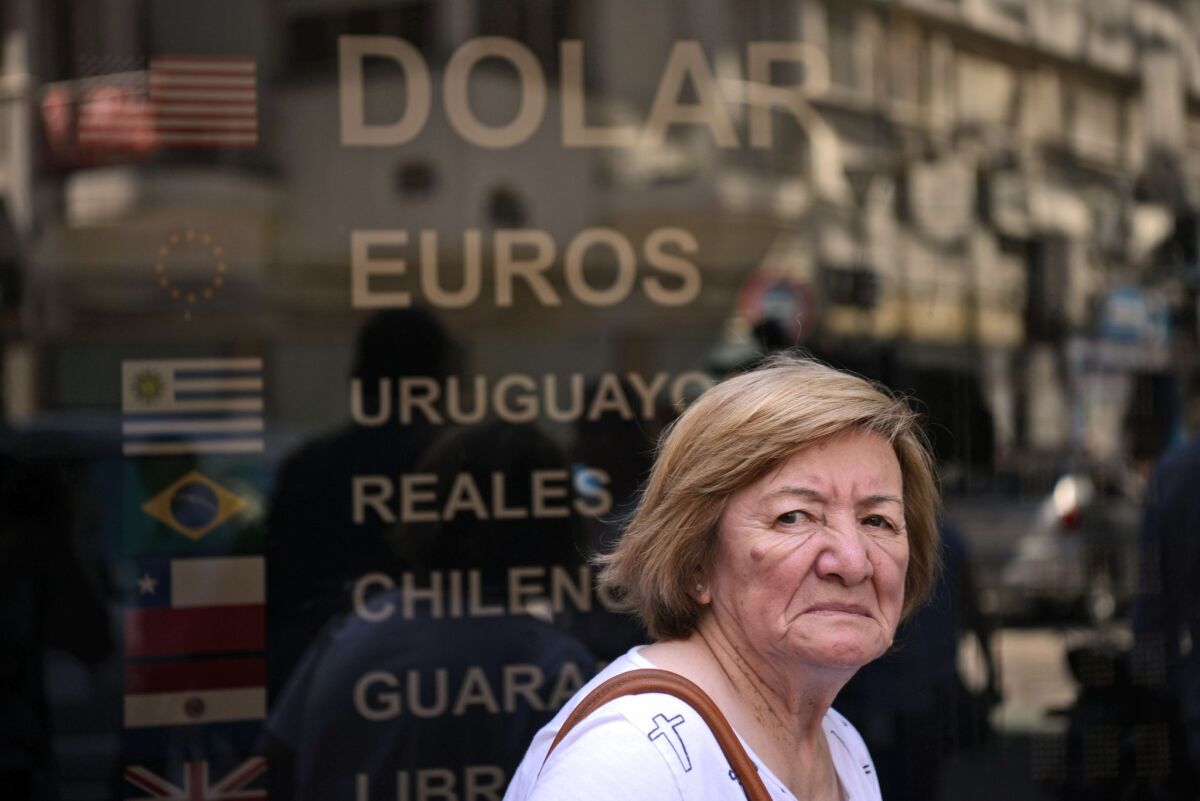 A pedestrian walks past a closed money-changing business in downtown Buenos Aires on Dec. 16, the date the new center-right government abolished the subsidized exchange rate for the Argentine peso.