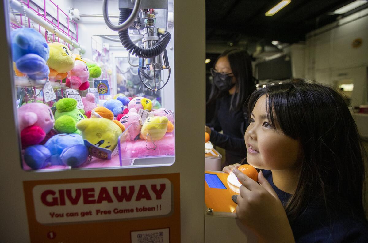 Jandy Ponvanit, 9, attempts to retrieve a Japanese capsule toy at the OC Japan Fair at OC Fair & Event Center.