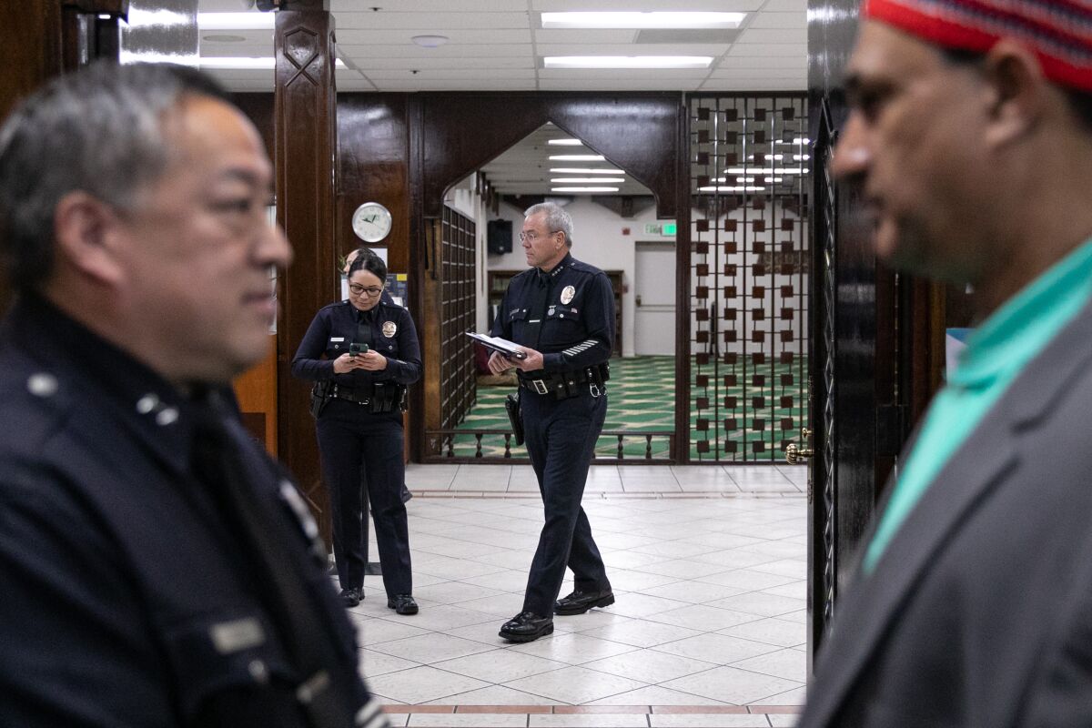 Three police officers and a man are standing in a mosque and are talking.