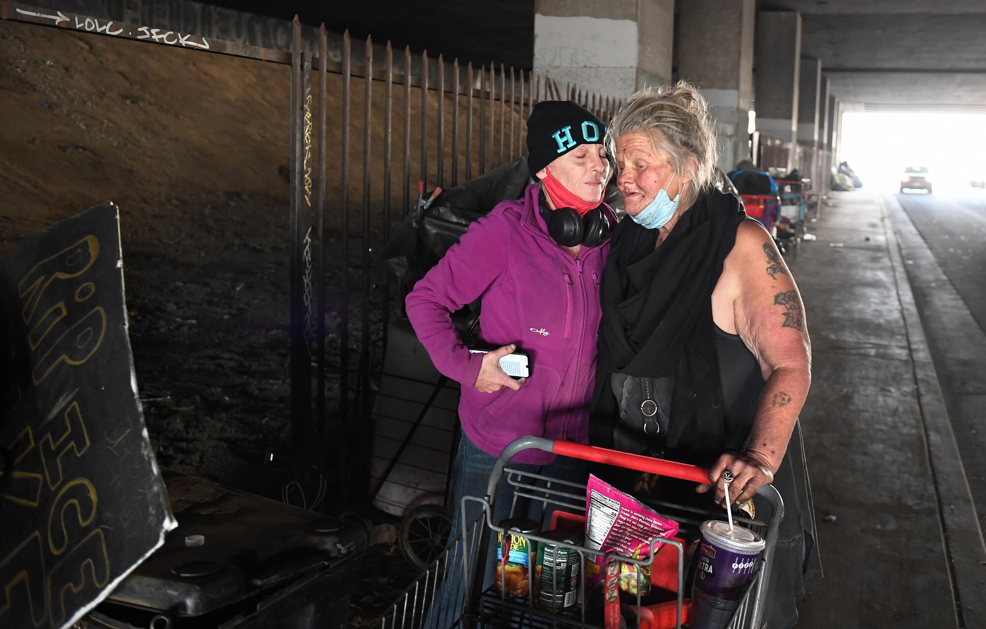 Homeless women embrace before leaving a homeless encampment.