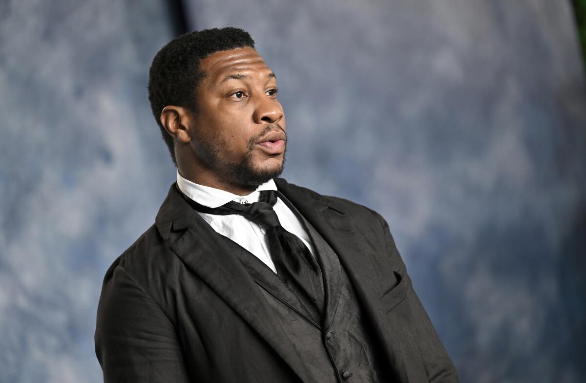 Jonathan Majors in a black suit and tie