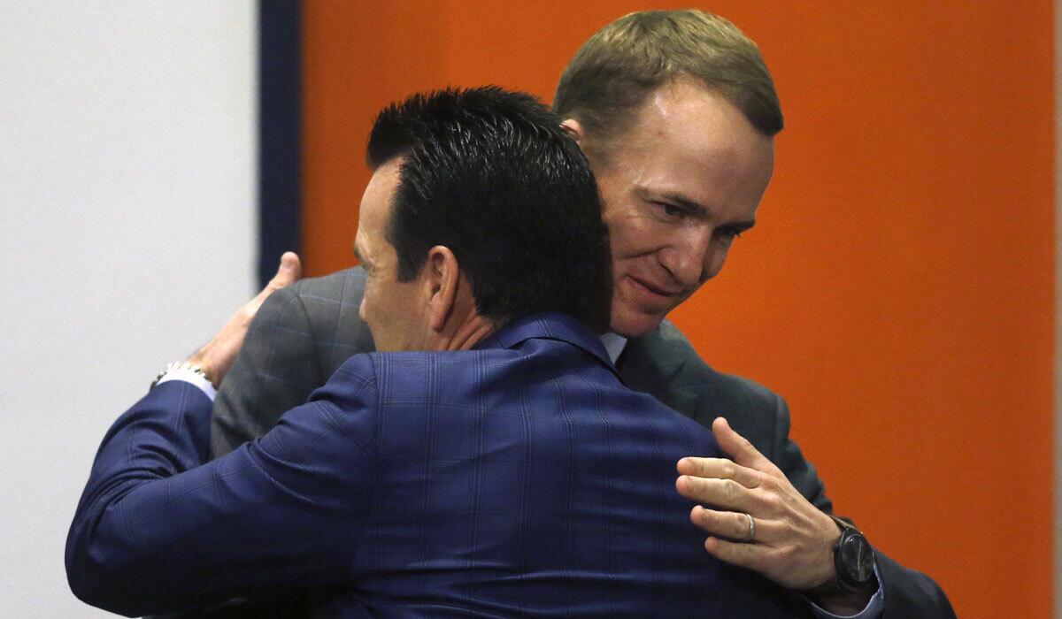 Peyton Manning, rear, hugs Broncos Coach Gary Kubiak during a news conference on Monday.