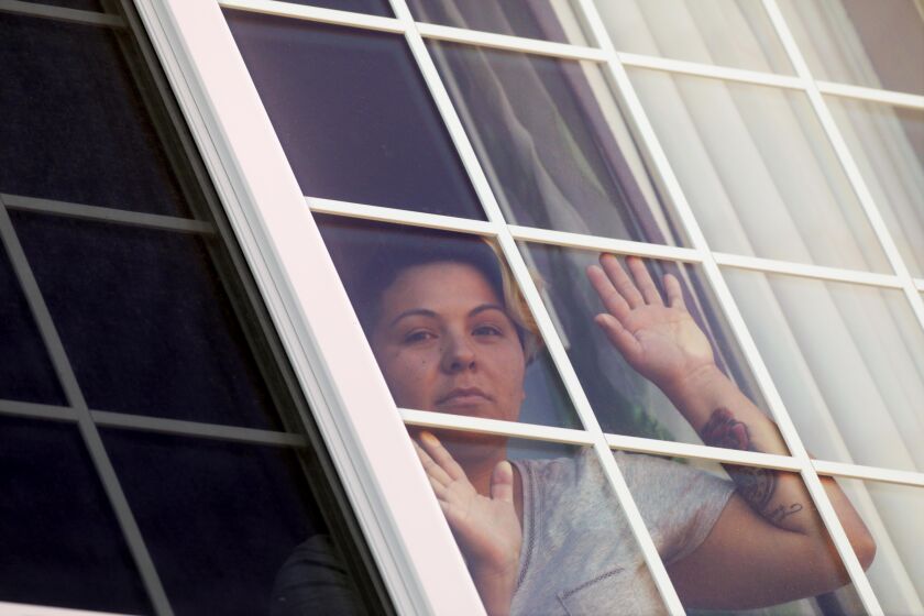 VISALIA, CA - APRIL 30, 2020 - - Maricela Ortiz, 31, who has COVID-19, looks out from her hotel room where she has been self-quarantined in Visalia on April 30. Ortiz, tested positive after she was released from Otay Mesa Detention Facility. She was denied a test despite having multiple symptoms while detained. Otay Mesa, which has one of the biggest COVID outbreaks of any detention facility in the country. Oritz, who has a few more days of quarantine, is looking forward to getting back to her husband and 2 sons. Her aunt has been delivering her meals at the hotel. (Genaro Molina / Los Angeles Times)