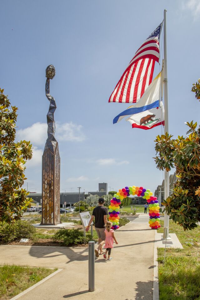 Karl Unnasch's "Burnt Matchstick" is seen opposite flags in the sculpture garden at Newport Beach’s Civic Center Park on Saturday.