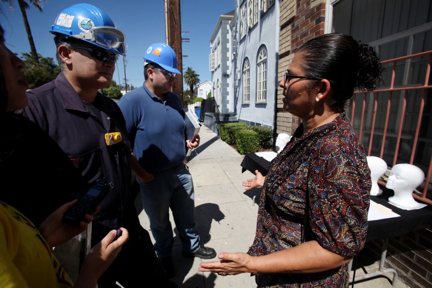 Paul Caballero, left, and Jose Enriquez, center, air quality inspectors with the AQMD, speak with Monic Uriarte in front of her building in the University Park neighborhood in Los Angeles.