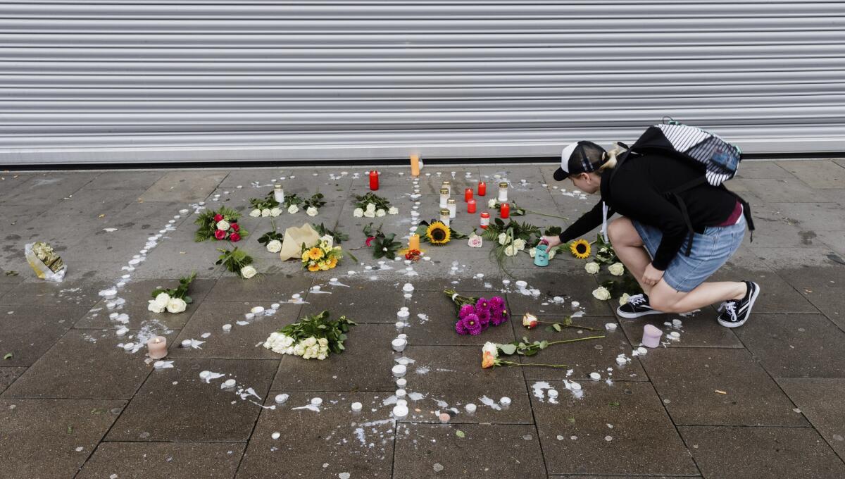A woman places flowers near a supermarket in Hamburg, Germany, where a man armed with a kitchen knife fatally stabbed one person and injured six others.