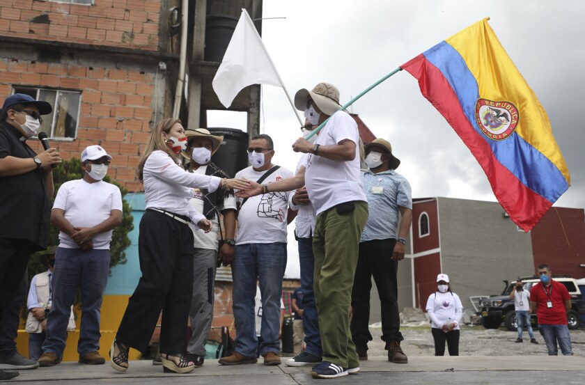 FILE - Rodrigo Granda, right, a former rebel commander and member of the FARC political party, shakes hands with Rocio Lopez, sister of two kidnap victims, who were eventually released, during a ceremony where former FARC members apologized to locals for the kidnappings they carried out over decades in the rural area of Pipiral near Villavicencio, Colombia, Oct. 29, 2020. The U.S. State Department on Tuesday, Nov. 30, 2021, revoked its designation of the FARC as a “foreign terrorist organization”, allowing U.S. officials to work with members of the rebel group as they continue to shift into political life. (AP Photo/Fernando Vergara, File)