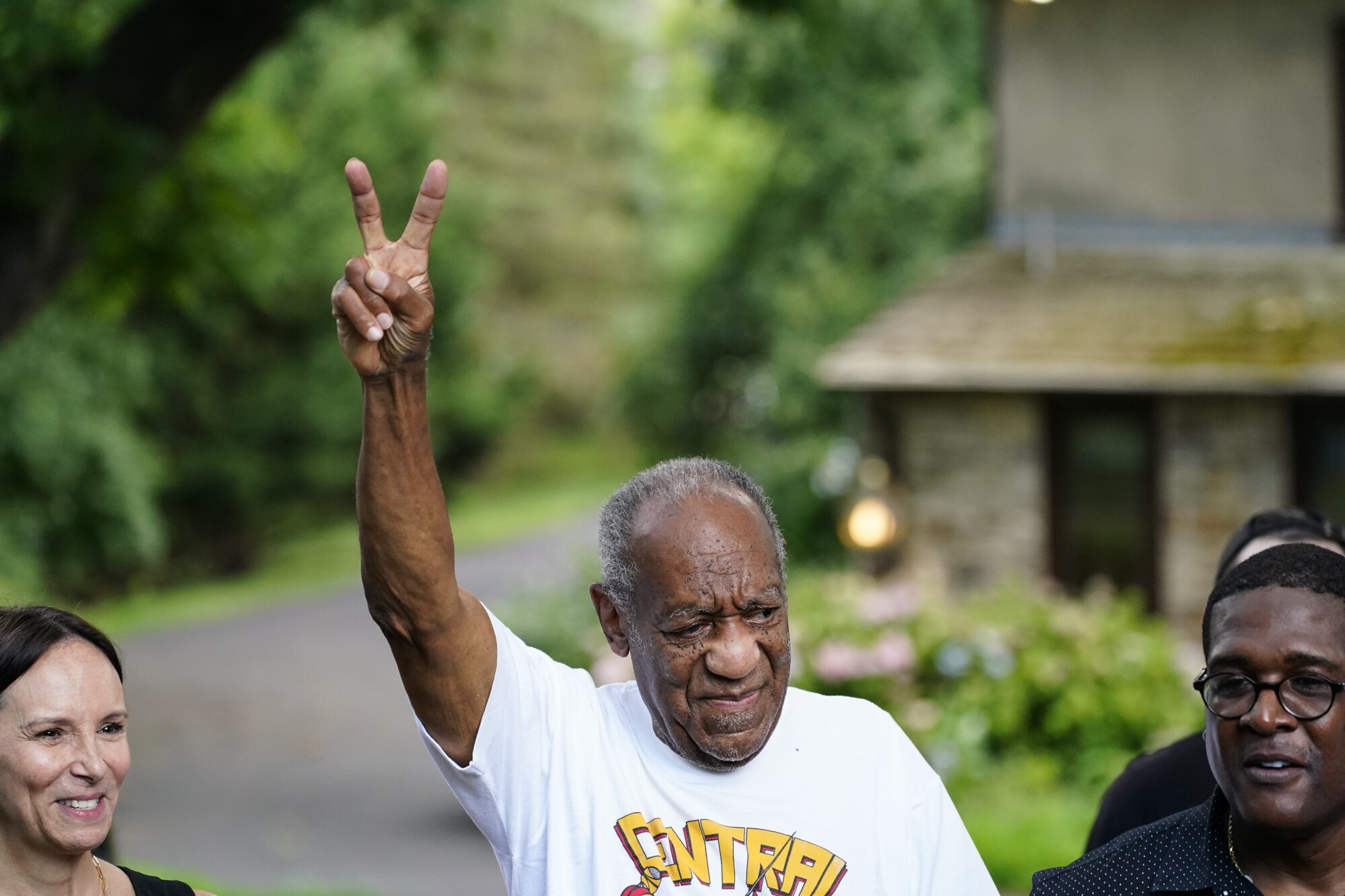 Bill Cosby gestures with a peace sign in the air