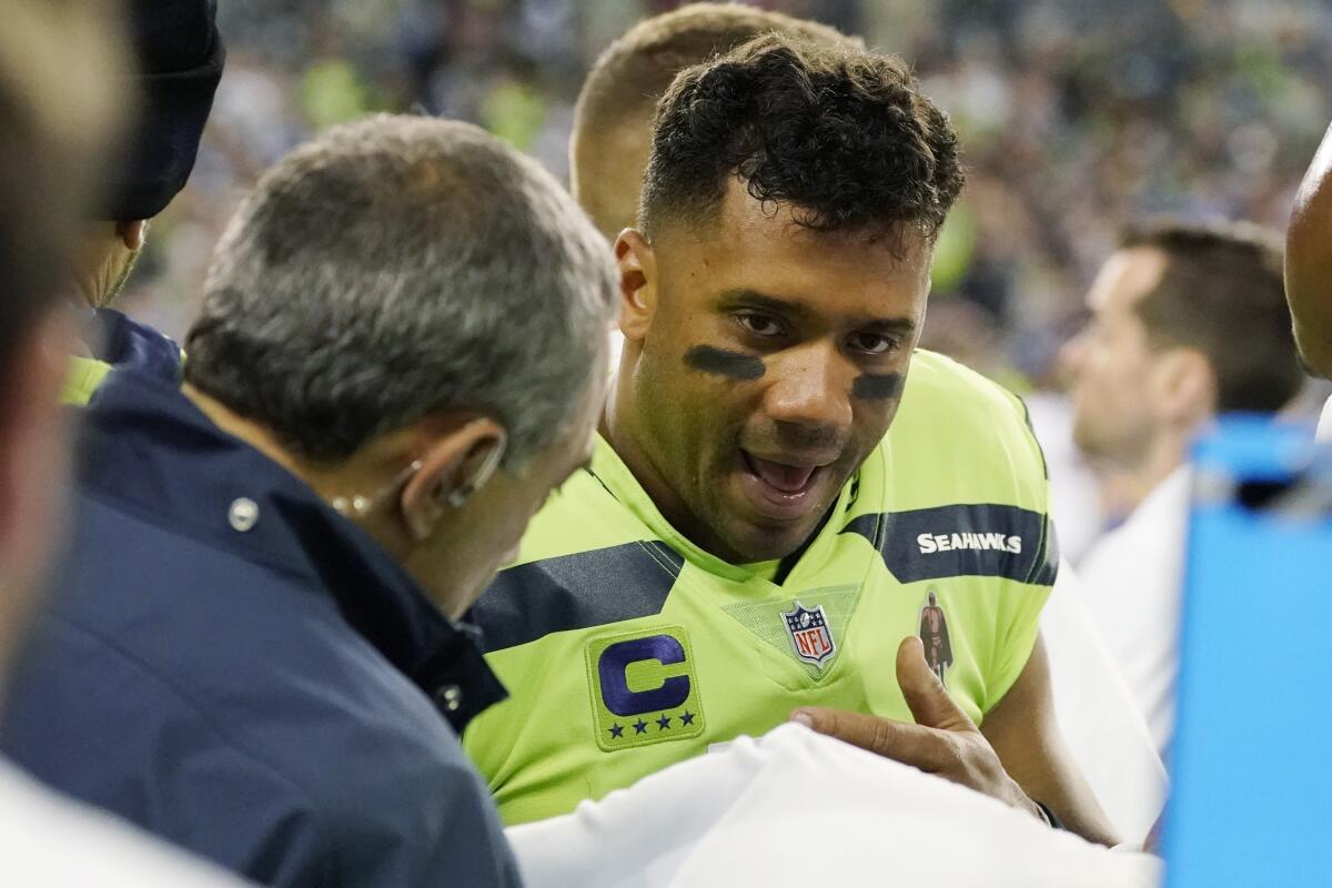 Seahawks quarterback Russell Wilson has his throwing hand examined on the sideline Thursday night in Seattle.
