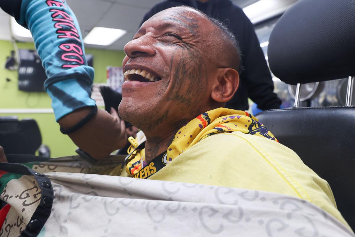 A man in a barber's chair smiles.
