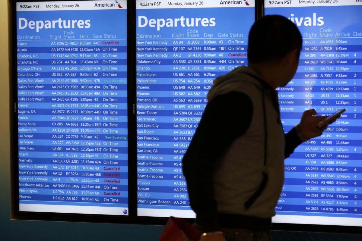 A traveler checks on flight departures and arrivals for American Airlines at Los Angeles International Airport. Travel agents continue to be in demand among travelers, who often ask unusual questions.