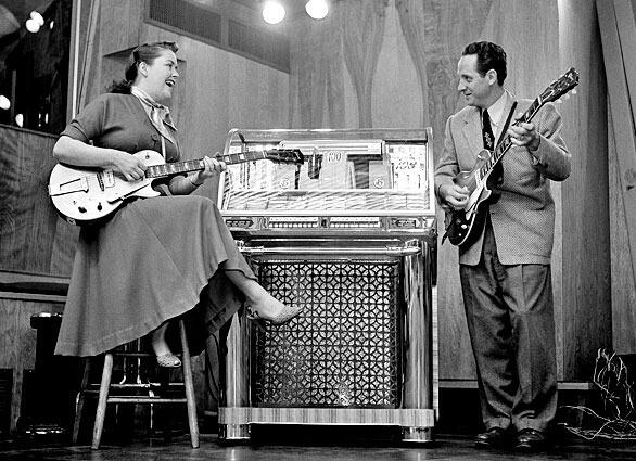 In 1953, Mary Ford and Les Paul strum in the television studio that serves as their workroom at their Oakland, N.J., home. The couple liked to test their records to see how they would sound to jukebox listeners.
