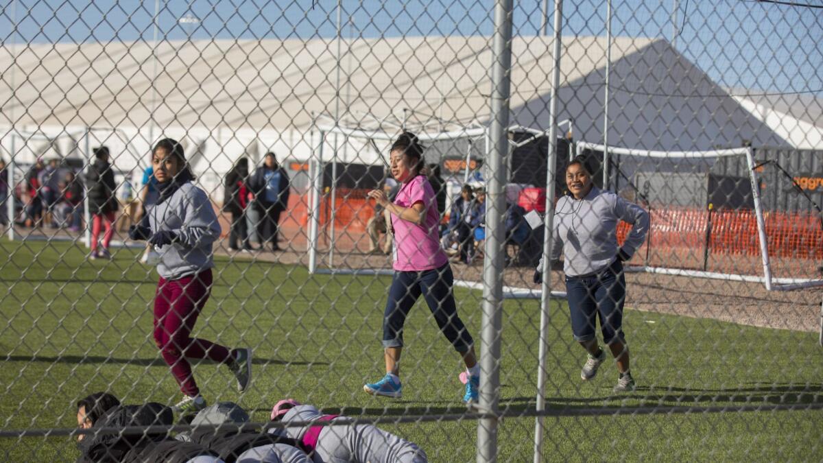 Migrant teens held inside the Tornillo detention camp run while looking at protesters waving at them outside the fences surrounding the facility in Tornillo, Texas. on Nov. 25, 2018.