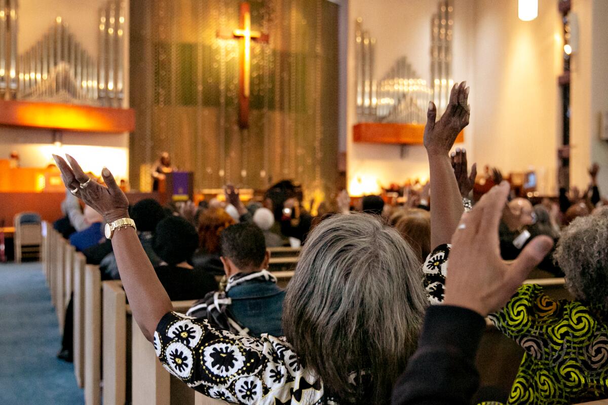 Community members and clergy outstretch their hands in support of Mark Ridley-Thomas.