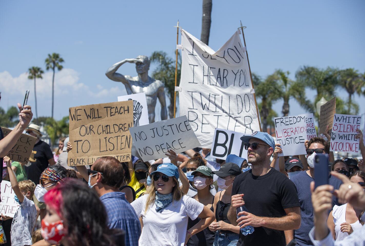 Demonstrators gather in front of the Ben Carlson Memorial in Newport Beach on Wednesday.