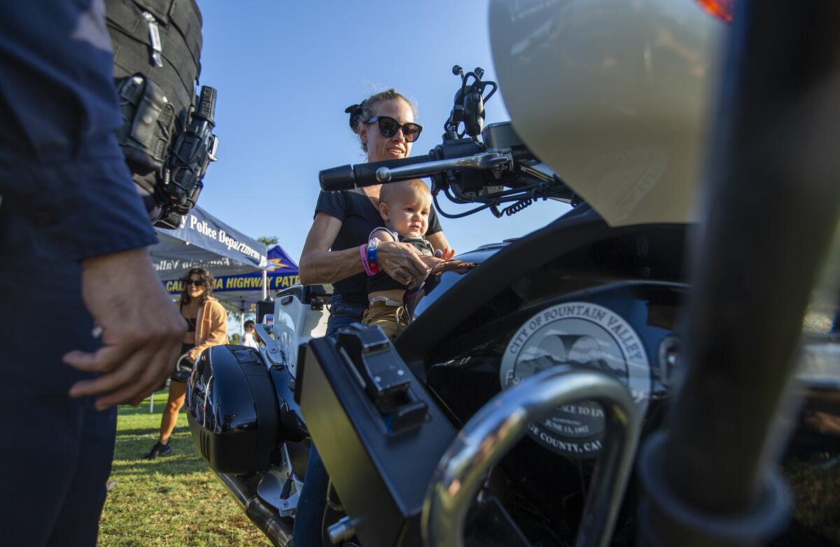 Kolett Mobrici holds her son Enzo while sitting on Fountain Valley motor officer Matt Spencer's motorcycle.