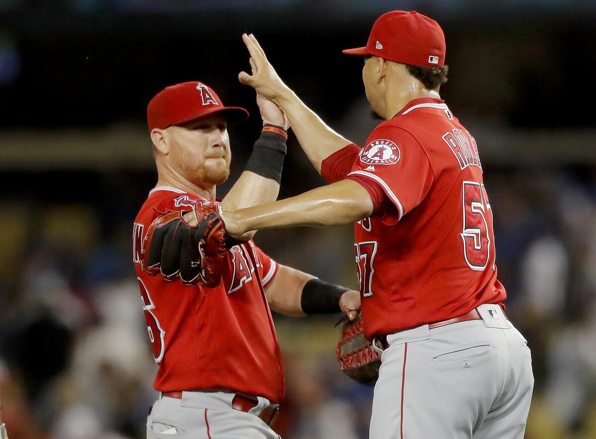 Angels right fielder Kole Calhoun and pitcher Hansel Robles celebrate a 3-2 victory over the Dodgers on Wednesday at Dodger Stadium.