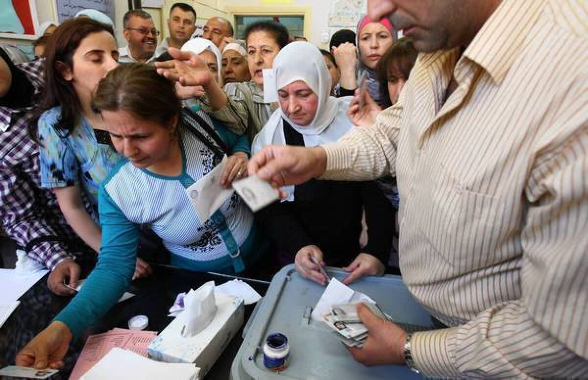 Syrian women have their identification checked before casting their votes in Damascus in parliamentary elections.