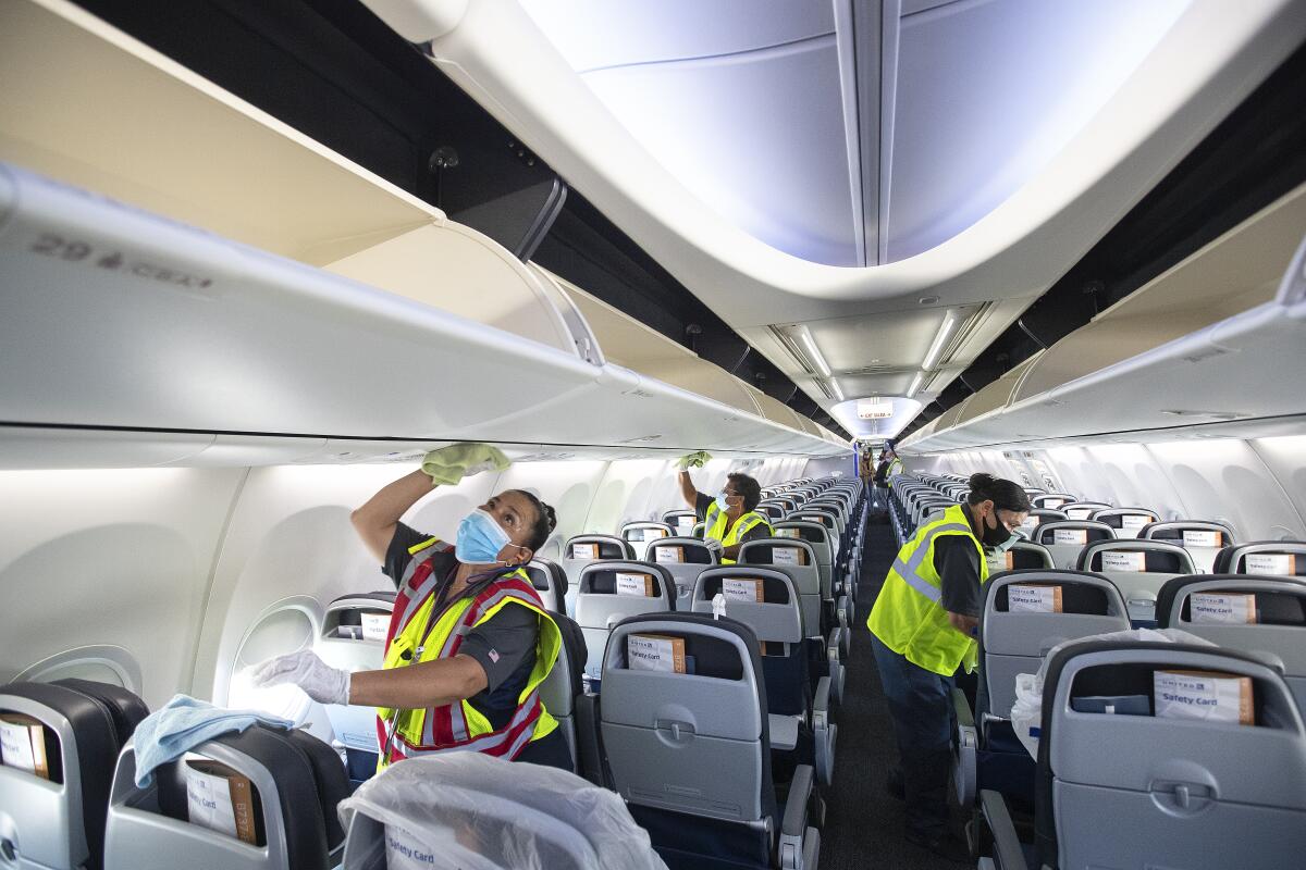 Workers clean the inside of a plane cabin 