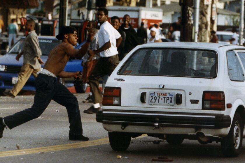 A rioter attacks a car on Florence and Normandie in Los Angeles after the King verdict 4/29/1992. Kirk McKoy / Los Angeles Times