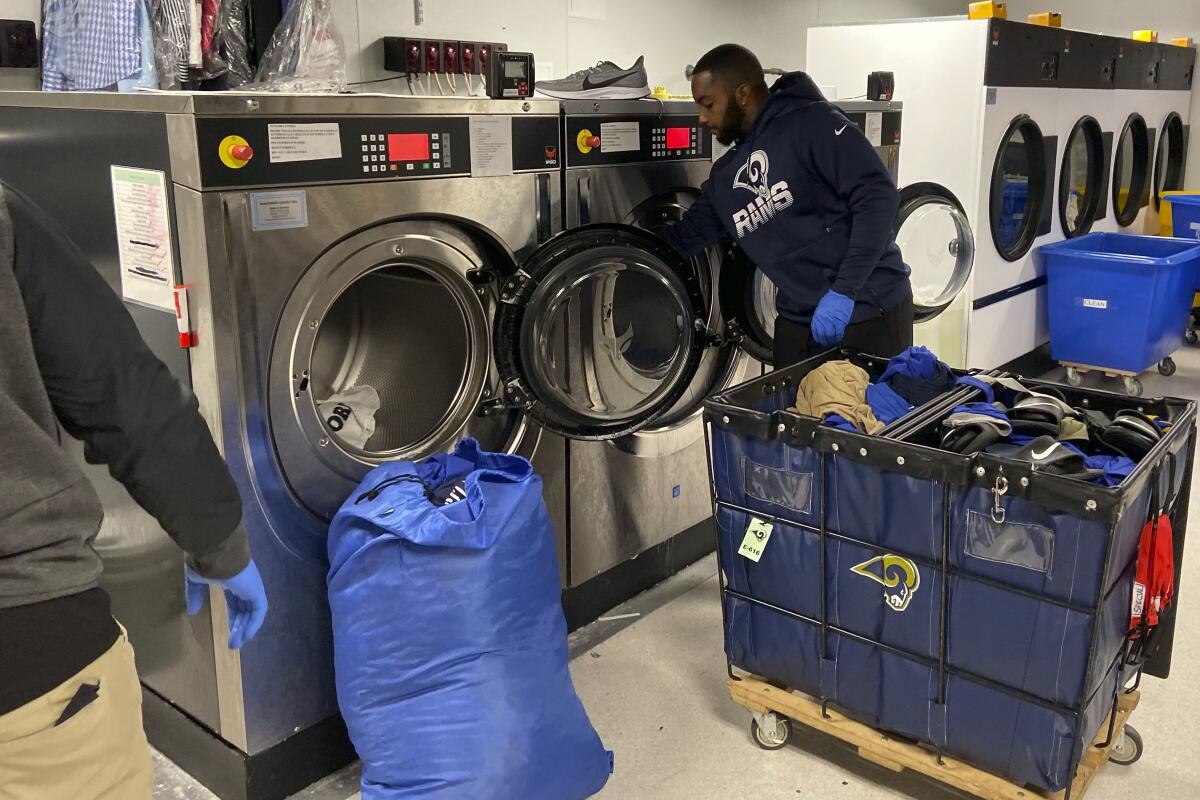 Equipment worker Dejo’N Rothschild loads laundry into the machines at team headquarters after the game.