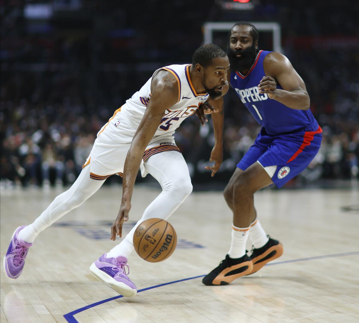 Phoenix Suns forward Kevin Durant drives past Clippers guard James Harden during the first half Monday.