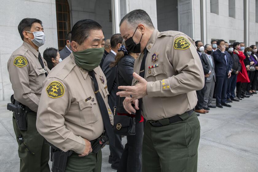 LOS ANGELES, CA - MARCH 25, 2021: Los Angeles County Sheriff Alex Villanueva, right, standing in front of the Hall of Justice in downtown Los Angeles, talks with L.A. County Undersheriff Tim Murakami before start of press conference with members of local Asian community groups in a show of solidarity and support for the local Asian American and Pacific Islander community. Villanueva called for zero tolerance for hate crimes and incidents in L.A. County. (Mel Melcon / Los Angeles Times)