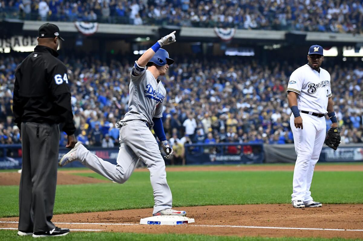 As Milwaukee Brewers first baseman Jesus Aquilar looks on, Dodgers' Cody Bellinger rounds first base after hitting a two-run home run in the second inning during the NLCS.
