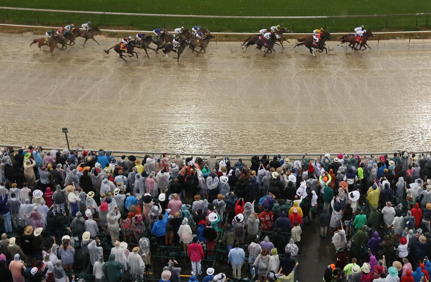 Spectators watch Promises Fulfilled, ridden by jockey Corey Lanerie, and Justify, with Mike Smith aboard, lead the field into the first turn during the 144th running of the Kentucky Derby.