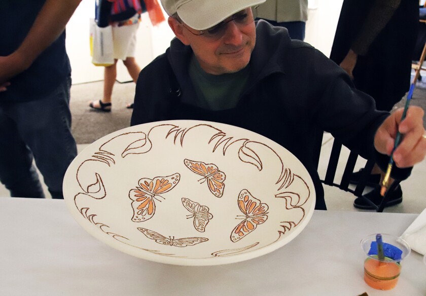 Mark Jacobucci from Laguna Niguel paints his set "monarch butterfly" at the Platter Painting Party
