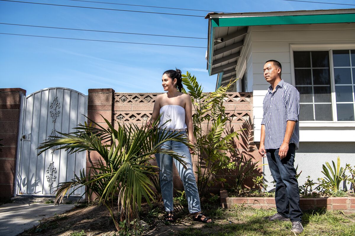 First-time home buyers Sarah and John Tran stand outside their home in North Long Beach