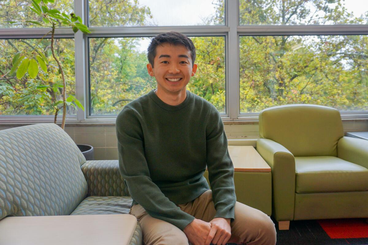 A young man sits on a couch.