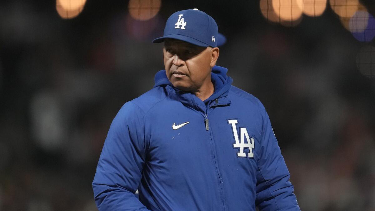 Los Angeles Dodgers' Dave Roberts walks in the dugout wearing a