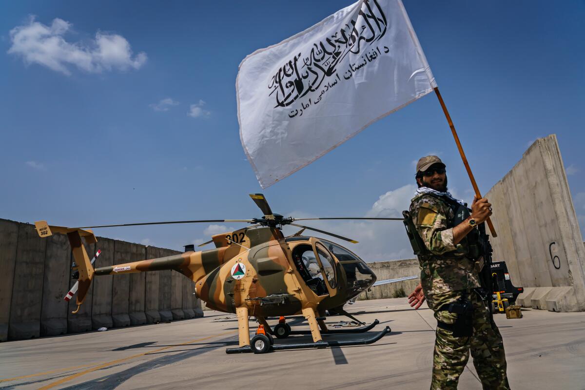 A Taliban fighter raises the movement's flag as they take a tour of the military assets that were left behind.