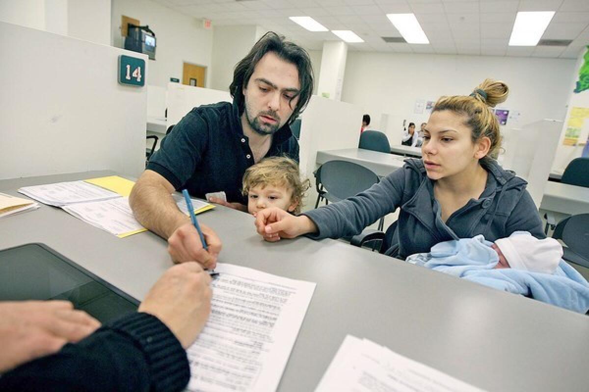 Greg and Karen, with their son Immanuel and infant Elijah, fill out paperwork at the Department of Public Social Services in Los Angeles. Greg was laid off in February from a suit store in Hollywood.