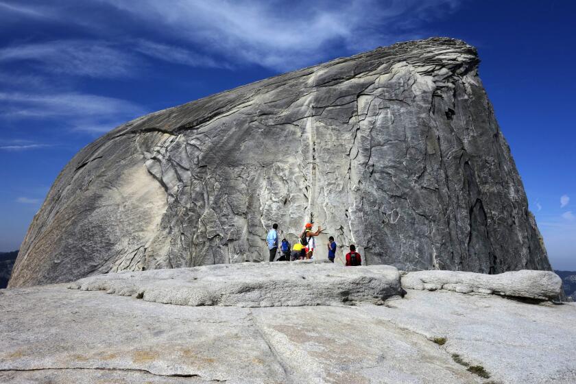 File - In this July 15, 2014, file photo, hikers gather in the foreground as climbers use the assistance of cables to scale Half Dome in Yosemite National Park National Park in California's Sierra Nevada. A hiker in Yosemite National Park fell to his death while climbing to the top of iconic granite cliffs of Half Dome. Park spokesman Scott Gediman says 29-year-old Danielle Burnett, of Lake Havasu City, Arizona, was scaling the steepest part of the trail Thursday, Sept. 5, 2019, when she fell more than 500 feet down the steep, rocky terrain. Gediman says Burnett was dead when Park Rangers arrived on the scene. (AP Photo/Brian Melley, File)