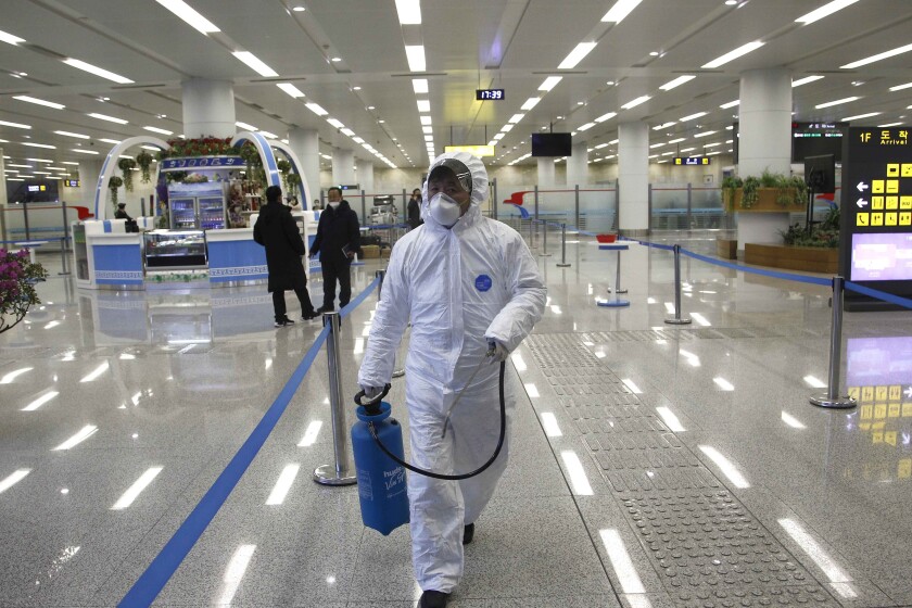 A staff worker with disinfectant sprays at the airport in Pyongyang, North Korea.