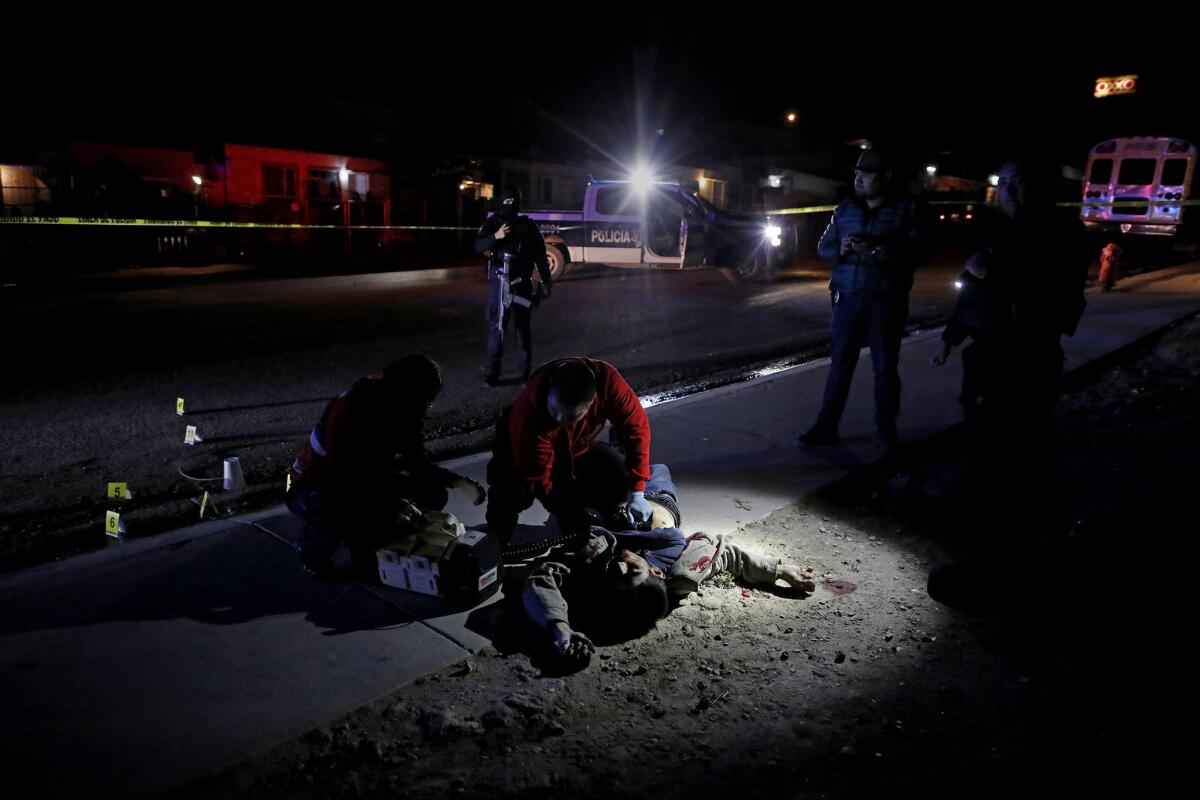 Tijuana Red Cross paramedics and police officers work at the scene of a homicide where a man around 28 was shot five times.