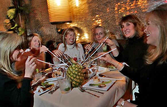 A group of women enjoy dinner and a scorpion bowl drink at Luau restaurant in Beverly Hills.