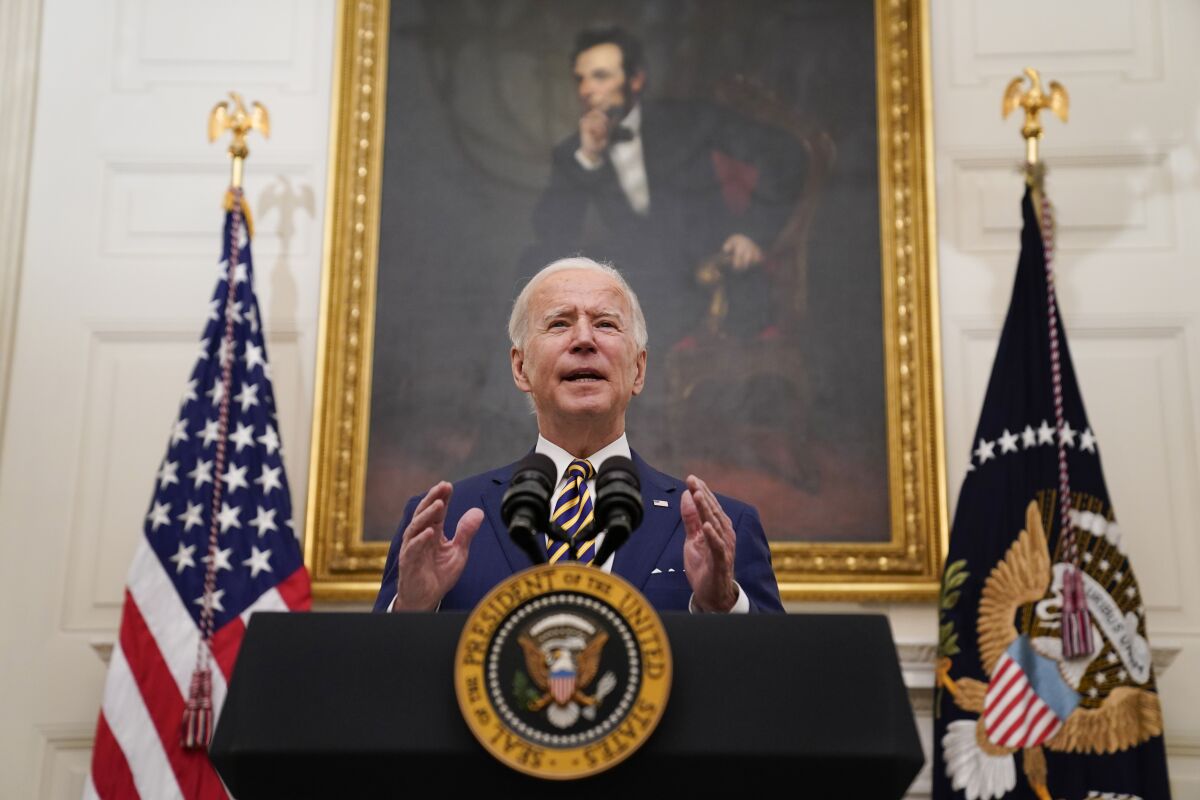 President Biden speaks at a lectern with flags and a painting of Abraham Lincoln behind him.