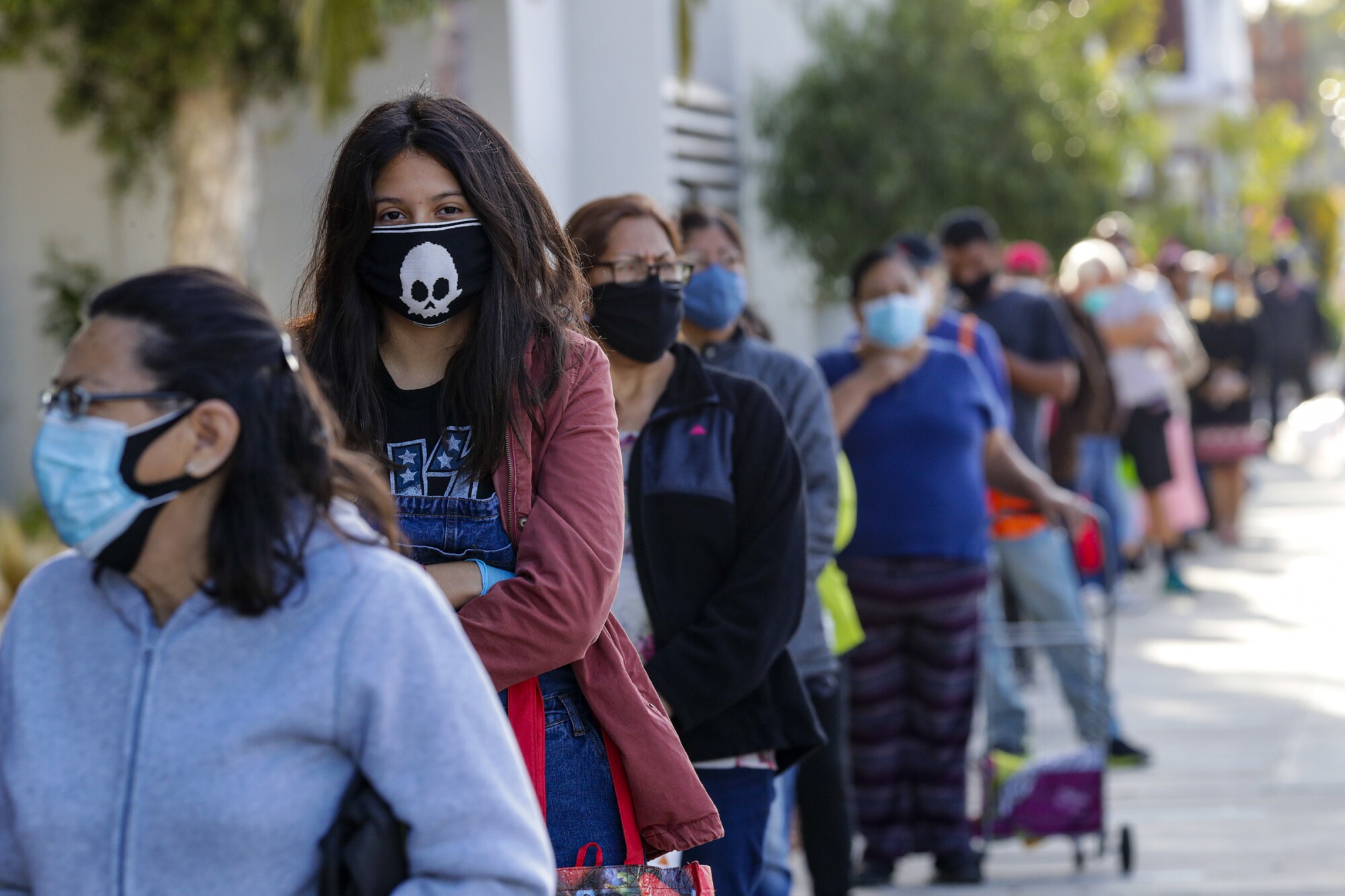 People wait in long line to get meal bags distributed by LAUSD at James A. Garfield High School in Los Angeles.