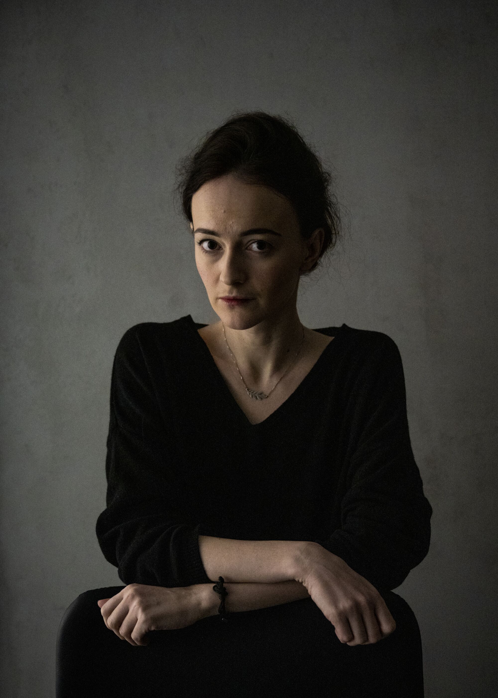 Une femme debout regarde la caméra avec une expression sérieuse.