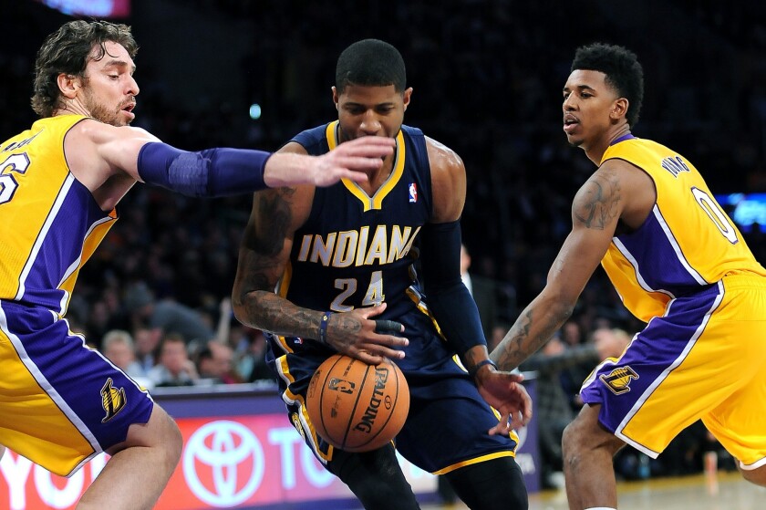 Indiana Pacers forward Paul George (24) loses control of the ball between Lakers teammates Pau Gasol, left, and Nick Young during a game last month at Staples Center.