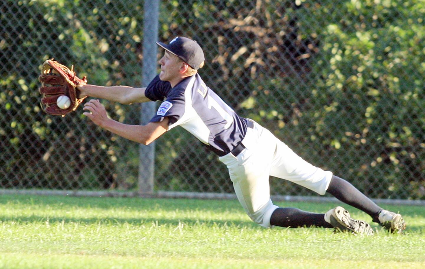 Crescenta Valley's centerfielder Troy Leef dives to make the catch in the first inning against Encino in a Little League Junior baseball Section 2 title baseball game at Dunsmore Field in Glendale on Wednesday, July 16, 2014.